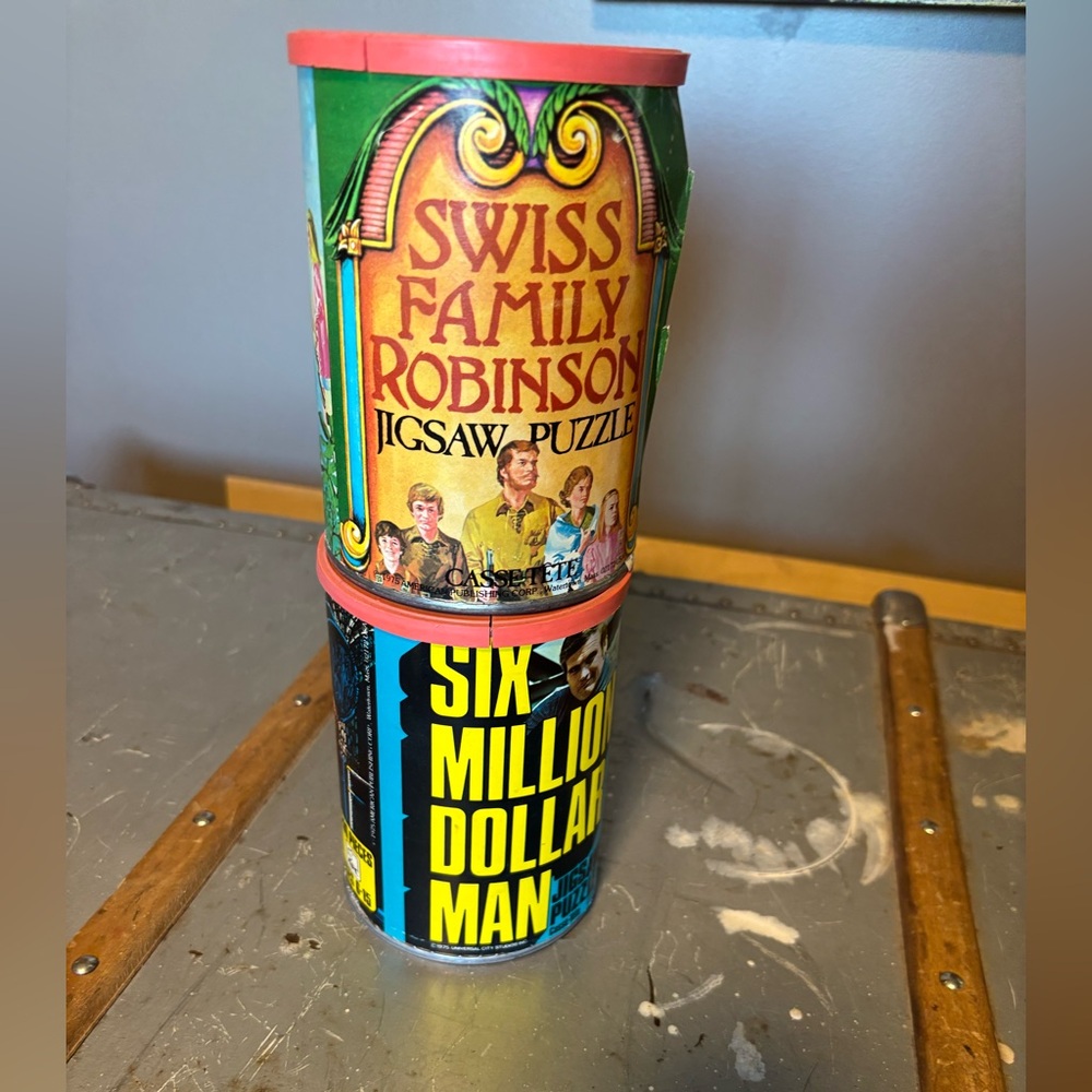 Two(2) vintage puzzle tins. Six Million Dollar Man. Swiss Family Robinson